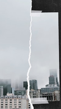 a black and white photo of a city with a torn piece of paper